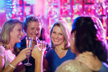 Smiling mature people toasting with champagne flutes in nightclub