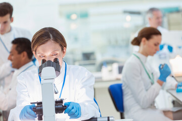 Scientist examining sample under microscope in laboratory