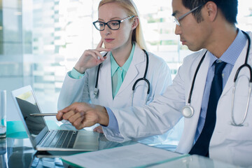 Doctors using laptop and discuss patient's treatment