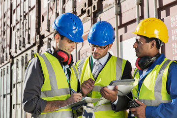 Businessmen and worker talking near cargo containers