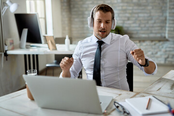 Male entrepreneur having fun while listening music over headphones in the office.