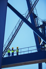 Low angle view of workers and businessman talking on cargo crane