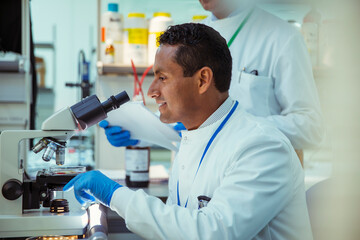 Scientist examining sample under microscope in laboratory