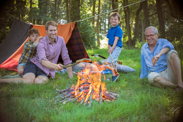 Boy, father and grandfather relaxing near campfire