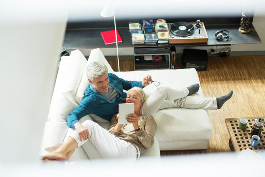 High angle view of older couple using digital tablet on sofa