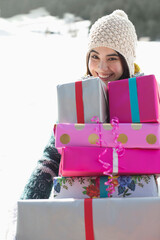 Portrait of smiling woman carrying stack of gifts