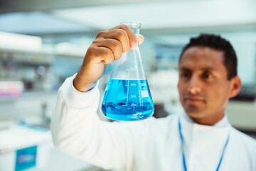 Scientist examining sample in beaker in laboratory