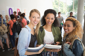 Portrait of university friends standing in corridor with books