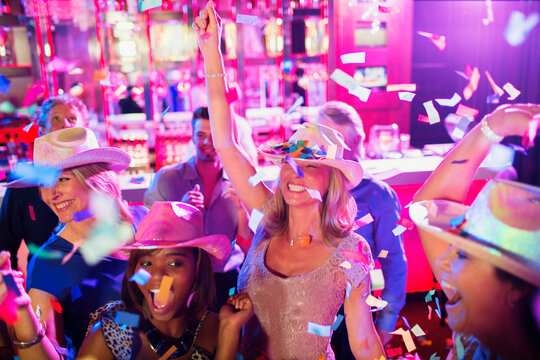 Confetti falling on women wearing cowboy hats dancing in nightclub
