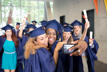 Students taking selfie after graduation ceremony - obrazy, fototapety, plakaty