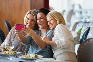 Three mature women taking selfie in restaurant