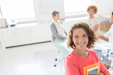 Obraz premium Portrait of smiling businesswoman in office, colleagues in background