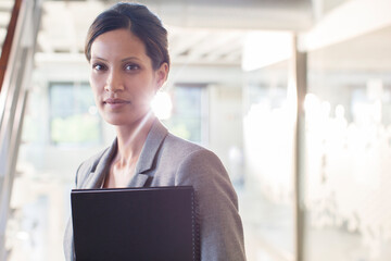 Portrait of businesswoman holding documents in office corridor