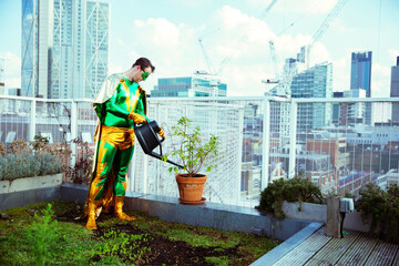 Superhero watering potted plant on city rooftop