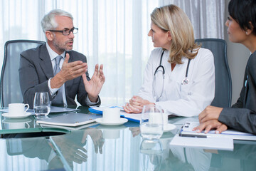 Obraz premium Female doctor, man and woman talking at table in conference room