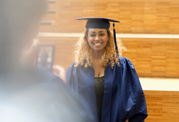 Female student in graduation gown posing for picture in university corridor