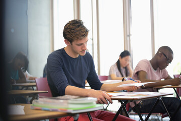 University student taking exam, students in background writing
