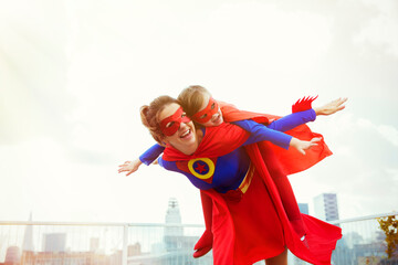 Superhero mother and daughter playing on city rooftop