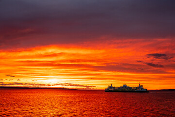 The silhouette of a ferry boat against a colorful sunset sky