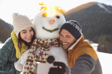 Couple taking selfie with snowman