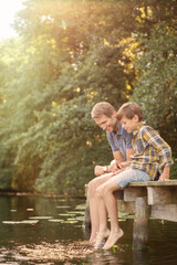 Father and son dangling feet in lake