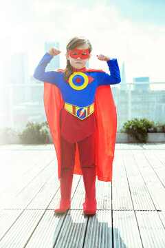 Superhero Girl Flexing Muscles On City Rooftop