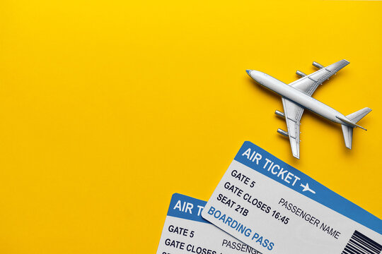 Toy plane with tickets on a yellow background with copy space.