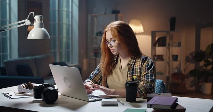 Cute caucasian girl concentrating on work at desk, using laptop to prepare for school or university exam, young freelancing manager working on a project 4k footage