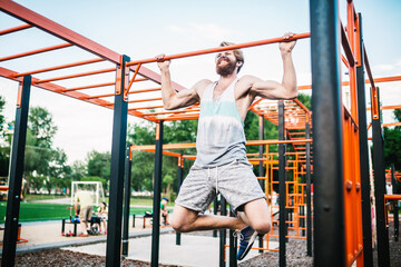 strong athlete doing pull-up on horizontal bar. Muscular man doing pull ups on horizontal bar in park. Gymnastic Bar During Workout. training strongmanoutdoor park gym. Man Doing Exercise gym Outdoor - Powered by Adobe
