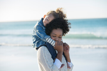 Mother carrying daughter on her shoulders on beach