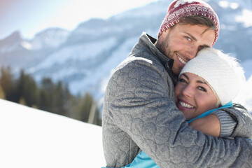 Portrait of smiling couple hugging in snow