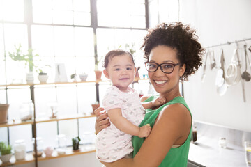 Mother holding her baby daughter in domestic kitchen