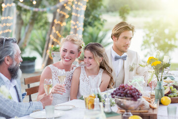 Young couple their guests sitting at table during wedding reception in garden