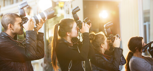 Paparazzi photographers  in a row pointing cameras at event