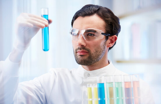 Man In Laboratory Looking At Vial With Blue Fluid