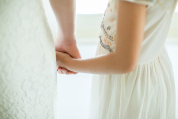 Bride holding bridesmaid's hand in domestic room