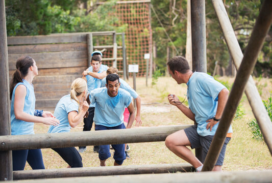 Teammates cheering man on boot camp obstacle course