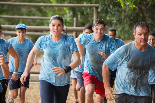 Team running in rain on boot camp obstacle course