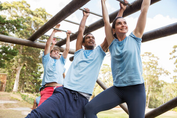 People crossing monkey bars on boot camp obstacle course