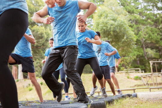 Determined people jumping tires on boot camp obstacle course - Powered by Adobe