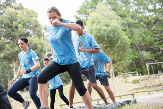 Determined people jumping tires on boot camp obstacle course