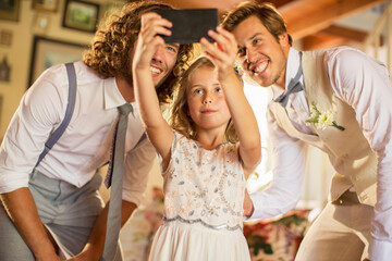 Bridegroom, best man bridesmaid photographing self in domestic room