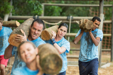 Determined team carrying logs on boot camp race course
