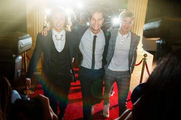 Portrait of smiling celebrities in a row arriving at red carpet event