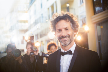 Portrait of celebrity at event with paparazzi in background