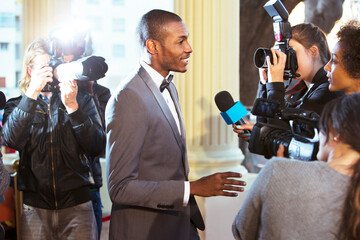 Celebrity being interviewed and photographed by paparazzi at event