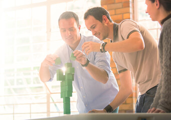 Businessmen balancing green blocks