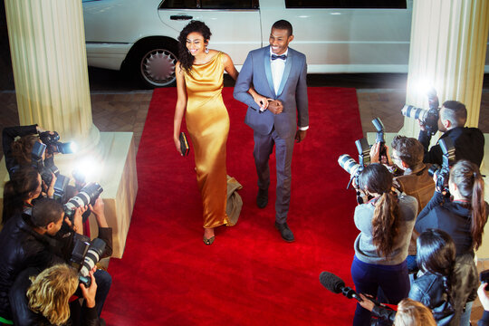 Celebrity couple arriving at red carpet event being photographed by paparazzi