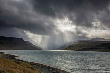 Sunbeams over cliffs and fjord, West Fjords, Iceland