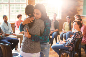 Women hugging in group therapy session - obrazy, fototapety, plakaty